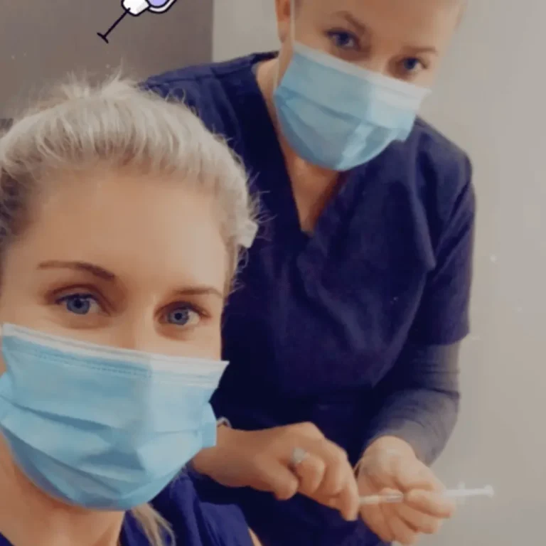 Two happy nurses wearing masks smiling at camera