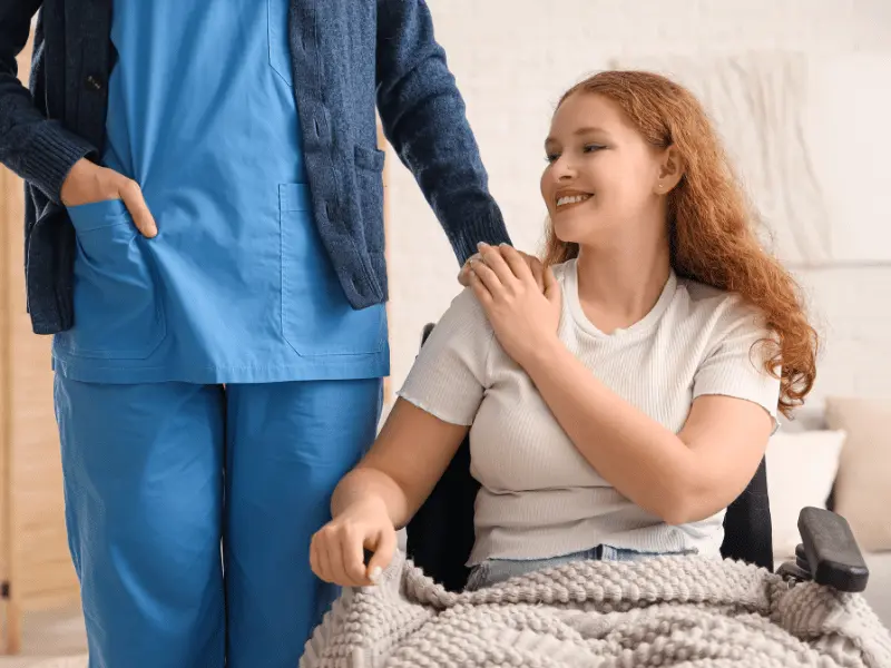 Disabled woman in wheelchair with nurse standing next to her